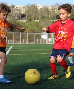 Children playing soccer in a youth league game on the field.